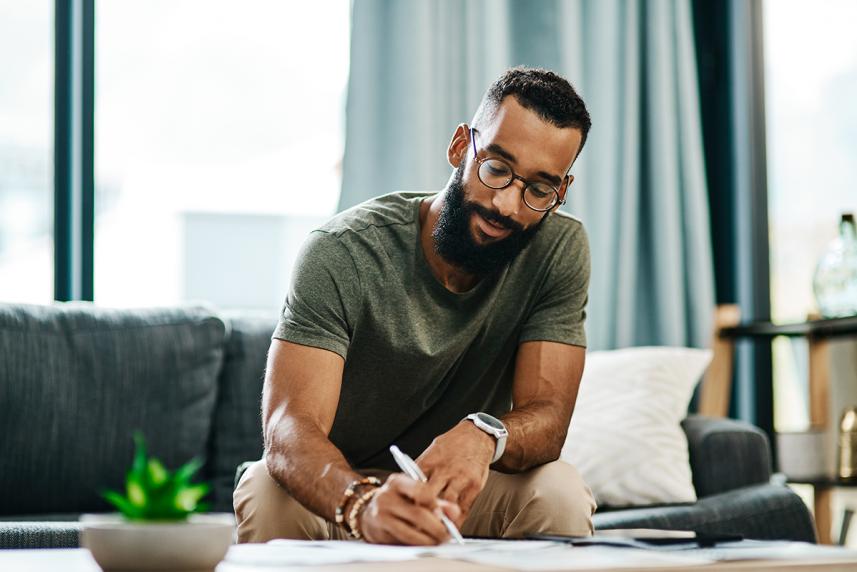 Man on couch writing.