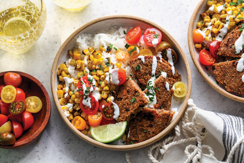 A Southwest black bean burger bowl on a table with a drink and napkin