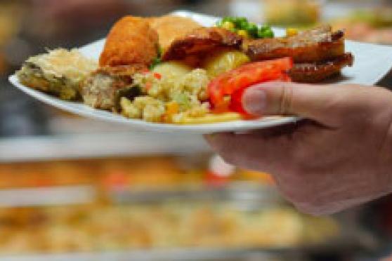 Photo: Hand holding plate full of food at buffet