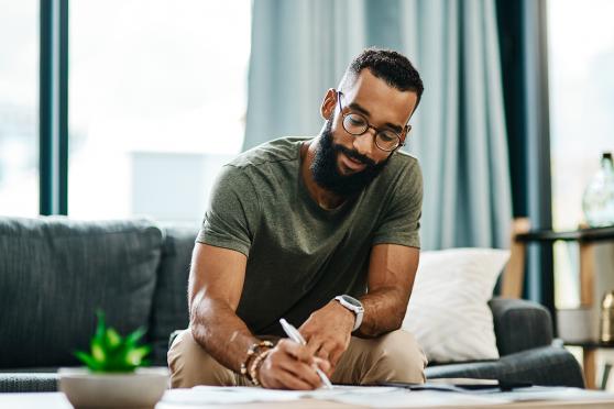 Man on couch writing.